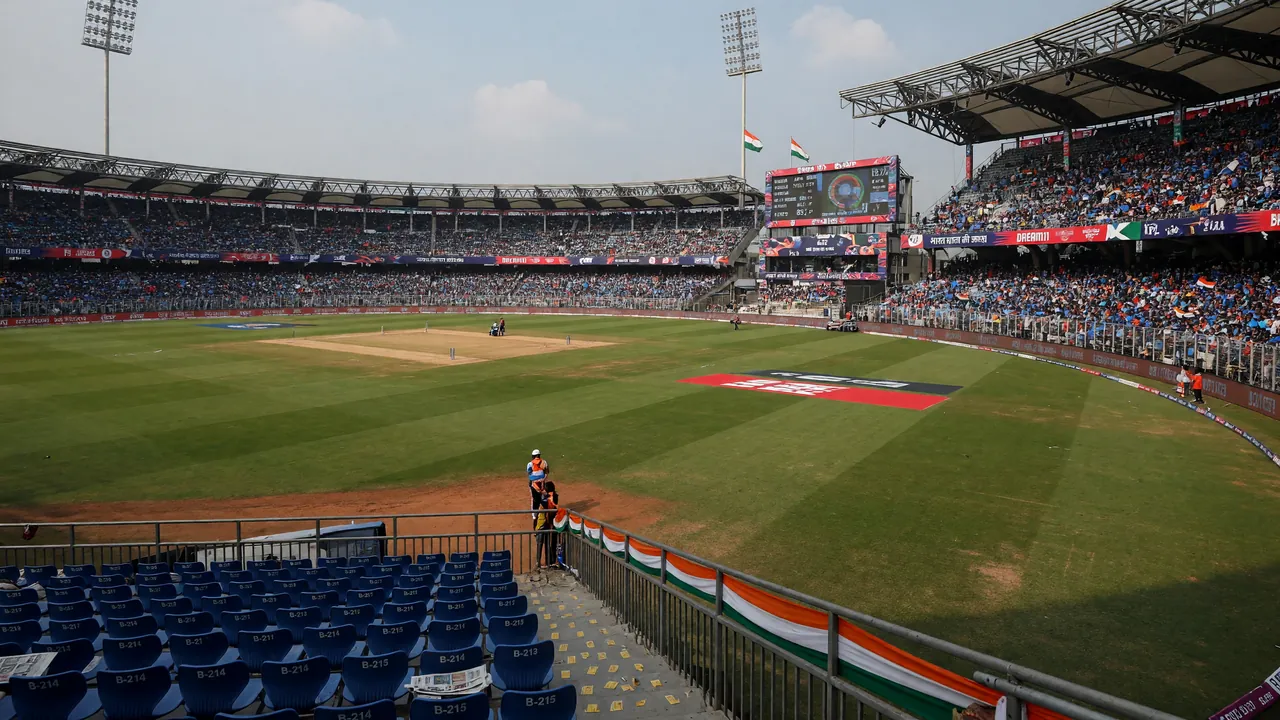 Editorial photograph of an Indian T20 cricket stadium during an afternoon match under daylight, lush outfield and stands in the background.